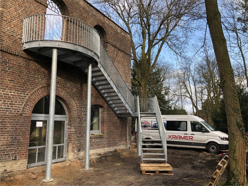 Baustelle des Hofs Alstaden, die Treppe ist bereits gebaut und an die Fassade angebracht. Im Hintergrund steht der Sprinter des Unternehmens Kramer.