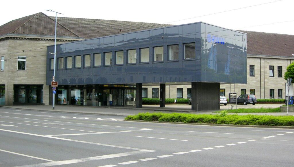 Ein Bild der Außenfassade des RWW Mülheims bei Tag. Das gesamte Gebäude ist sichtbar, das Bild wurde von der gegenüberliegenden Straßenseite gemacht. Die Außenfasse ist komplett über Panele abgedeckt.
